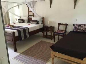 een slaapkamer met 2 bedden en een stoel. bij Nakupenda Malaika Flat in Pwani Mchangani