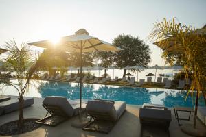 a swimming pool with lounge chairs and an umbrella at Dreams Corfu Resort & Spa - All Inclusive in Gouvia