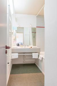 a white bathroom with a sink and a mirror at CERISE Dax - Les Jardins du Lac in Saint-Paul-lès-Dax