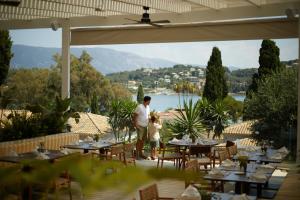 un hombre y un niño parados en un patio con mesas en Dreams Corfu Resort & Spa - All Inclusive en Gouvia