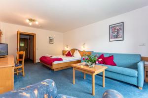 a living room with a couch and a bed at Hotel Unser Unterberg in Maria Alm am Steinernen Meer