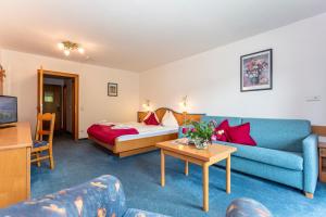 ein Wohnzimmer mit einem Sofa und einem Bett in der Unterkunft Hotel Unser Unterberg in Maria Alm am Steinernen Meer