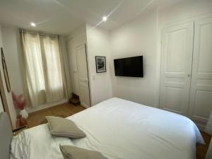 a white bedroom with a bed and a flat screen tv at CASA DOLCE in Amiens