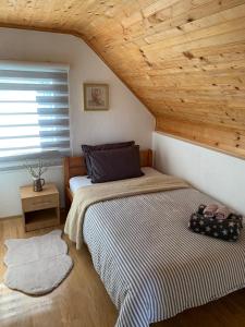 een slaapkamer met 2 bedden en een houten plafond bij Planinska kuća za odmor Perić in Prozor