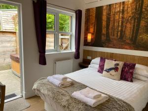 1 dormitorio con 1 cama con toallas en Badger Lodge with Hot Tub, en Cupar