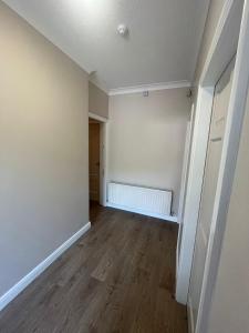um quarto vazio com piso de madeira e paredes brancas em Yeats Lodge Self catering Apartment and Bar em Galway