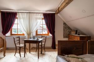 1 dormitorio con mesa, sillas y ventanas en Notranjska hiša - traditional country house, close to the world attraction Cerknica lake, en Begunje pri Cerknici