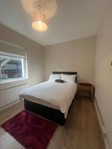 a bedroom with a large white bed with a purple rug at Yeats Lodge Self catering Apartment and Bar in Galway