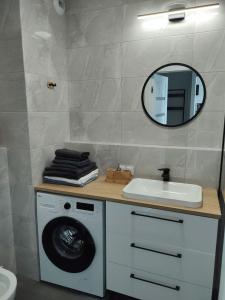 a bathroom with a washing machine and a mirror at TOTU TODAY-STARA CEGIELNIA APARTAMENTY, Faktura VAT, self check-in in Poznań