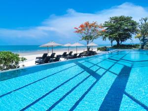 a swimming pool with chairs and umbrellas on the beach at Baba Beach Club Hua Hin Luxury Pool Villa by Sri panwa in Cha Am