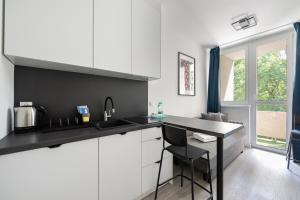 a kitchen with white cabinets and a black counter top at Wola Comfort Studio #1 in Warsaw