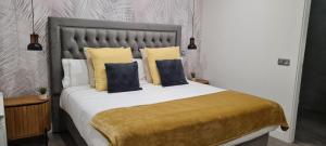 1 dormitorio con 1 cama grande con almohadas amarillas en Apartamentos Cava Baja en Madrid