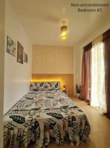 a bedroom with a bed with a comforter on it at Muji-inspired Home, 2-BR Bungalow Home Trece Martires in Trece Martires