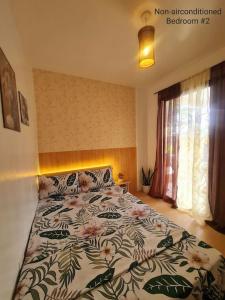 1 dormitorio con 1 cama con colcha de flores en Muji-inspired Home, 2-BR Bungalow Home Trece Martires, en Trece Martires