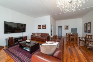 sala de estar con muebles de cuero y TV de pantalla plana en 60 on Montagu, en Mossel Bay