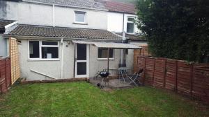 a house with a table and a grill in a yard at 3 Bedroom House for Brecons and Bike Park Wales in Merthyr Tydfil