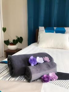 a bed with a blanket and purple flowers on it at R Garden Villa au calme de Baie du tombeau, Appartement familiale de 2 chambres et cuisine in Baie du Tombeau