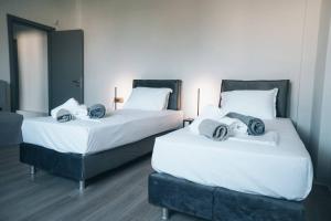 2 łóżka w pokoju z białą pościelą i poduszkami w obiekcie Rio Deluxe Villa w mieście Áyios Yeóryios