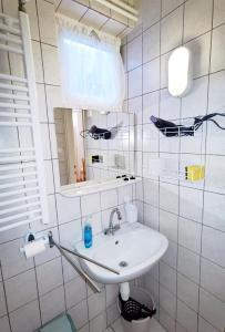 ein weißes Badezimmer mit einem Waschbecken und einem Spiegel in der Unterkunft Family Vendégház in Hajdúszoboszló