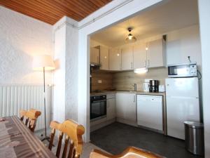 eine Küche mit weißen Schränken und einem Tisch mit Stühlen in der Unterkunft Appartement Chamrousse, 3 pièces, 8 personnes - FR-1-340-169 in Chamrousse