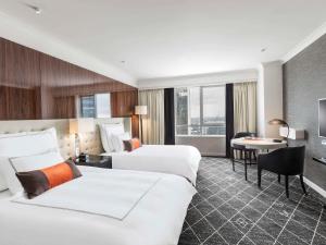 a hotel room with two beds and a desk at Swissotel Sydney in Sydney