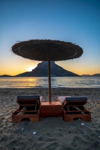 two lounge chairs and an umbrella on a beach at Plaza Hotel in Masouri