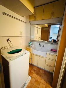 uma casa de banho com uma máquina de lavar roupa e um lavatório em 貸切 一戸建て古民家 3部屋 静か em Osaka