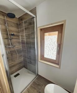 a bathroom with a shower with a window and a toilet at Chalet L'Albaron in La Toussuire