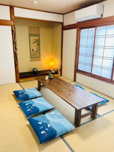 um quarto com uma mesa de madeira e tapetes azuis em 貸切 一戸建て古民家 3部屋 静か em Osaka
