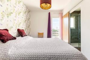 een slaapkamer met een groot wit bed met rode kussens bij Appartement Maeva in Saint-Pée-sur-Nivelle