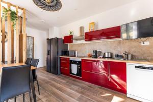 Appartement Maeva في سانت-بول-سور-نيفيل: مطبخ مع دواليب حمراء وطاولة مع كراسي