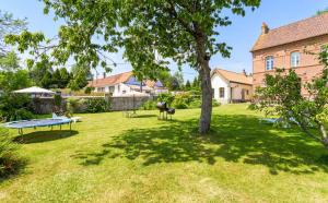 un patio con una mesa y un árbol y una casa en Le presbytère de Fressin, en Fressin