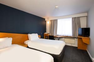 a hotel room with two beds and a tv at Holiday Inn Express Swansea East by IHG in Swansea