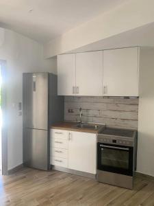 a kitchen with white cabinets and a stainless steel refrigerator at Litsa Apartments in Fourka