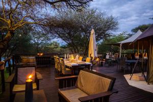 eine Terrasse mit Tischen, Stühlen und einem Sonnenschirm in der Unterkunft Taranga Safari Lodge in Rundu