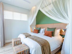 2 camas en un dormitorio con una pared verde en Miombo Mews en Victoria Falls