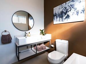 La salle de bains est pourvue d'un lavabo blanc et d'un miroir. dans l'établissement Miombo Mews, à Victoria Falls