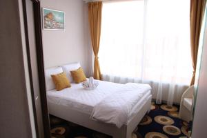 a bedroom with a bed with white sheets and yellow pillows at Bella Marina in Băltenii de Sus