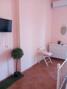 a room with a tv and a chair and a dresser at La Suite dei Ricami in Agrigento