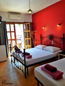 una camera con due letti e una parete rossa di EVANS Skiathos a Città di Skiathos