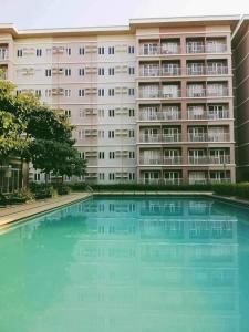 um grande edifício com uma grande piscina em frente em Trees Residence in Quezon City with balcony. em Manila
