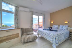 een slaapkamer met een bed, een stoel en een raam bij Ocean Hill - Ocean View, Terrace, BBQ, WIFI in Adeje