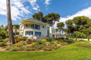 une grande maison blanche avec des arbres et de l'herbe dans l'établissement Luxueuse Villa Charleston - Vue mer, Sauna Hammam, à Antibes