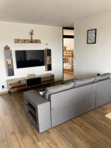 a living room with a gray couch and a flat screen tv at Parenthèse à la mer in Équihen-Plage