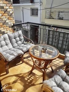 un patio con divano e un tavolo in vetro sul balcone. di EVANS Skiathos a Città di Skiathos
