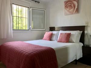 Apartamento Begur (costa brava) في بيغور: غرفة نوم بسرير ومخدات وردية ونافذة