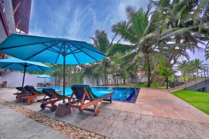 a swimming pool with chairs and umbrellas next to a pool at Rockside Beach Resort in Bentota