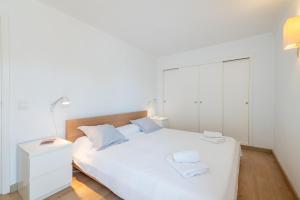 um quarto com uma cama branca e um armário branco em El Barco em Port de Pollença