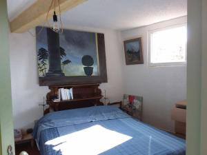 a bedroom with a blue bed and a window at Charme centre historique 17e siècle in Aramon