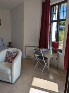 een woonkamer met een bank, een tafel en een stoel bij Les Jolis Nids - Studio Rouge Gorge in La Roche-Posay